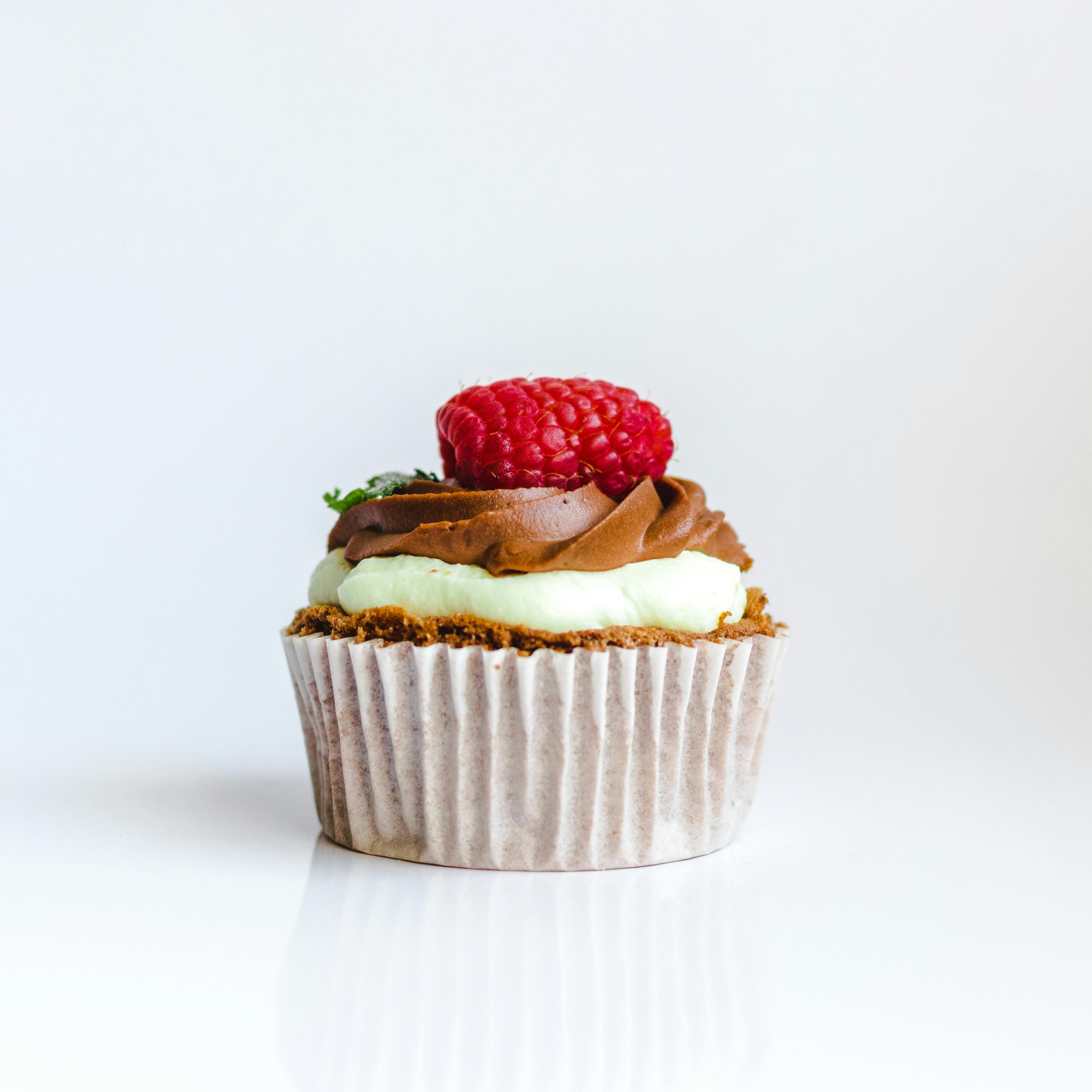 A delightful chocolate cupcake topped with raspberry and creamy frosting, perfect for dessert lovers.